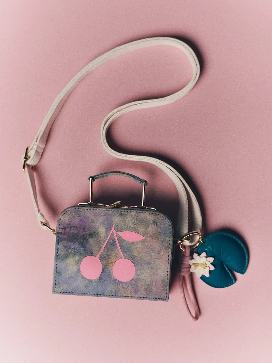 Pequeña maleta de Bonpoint x MoMA con estampado de nenúfares, motivo de cereza y llavero de piel