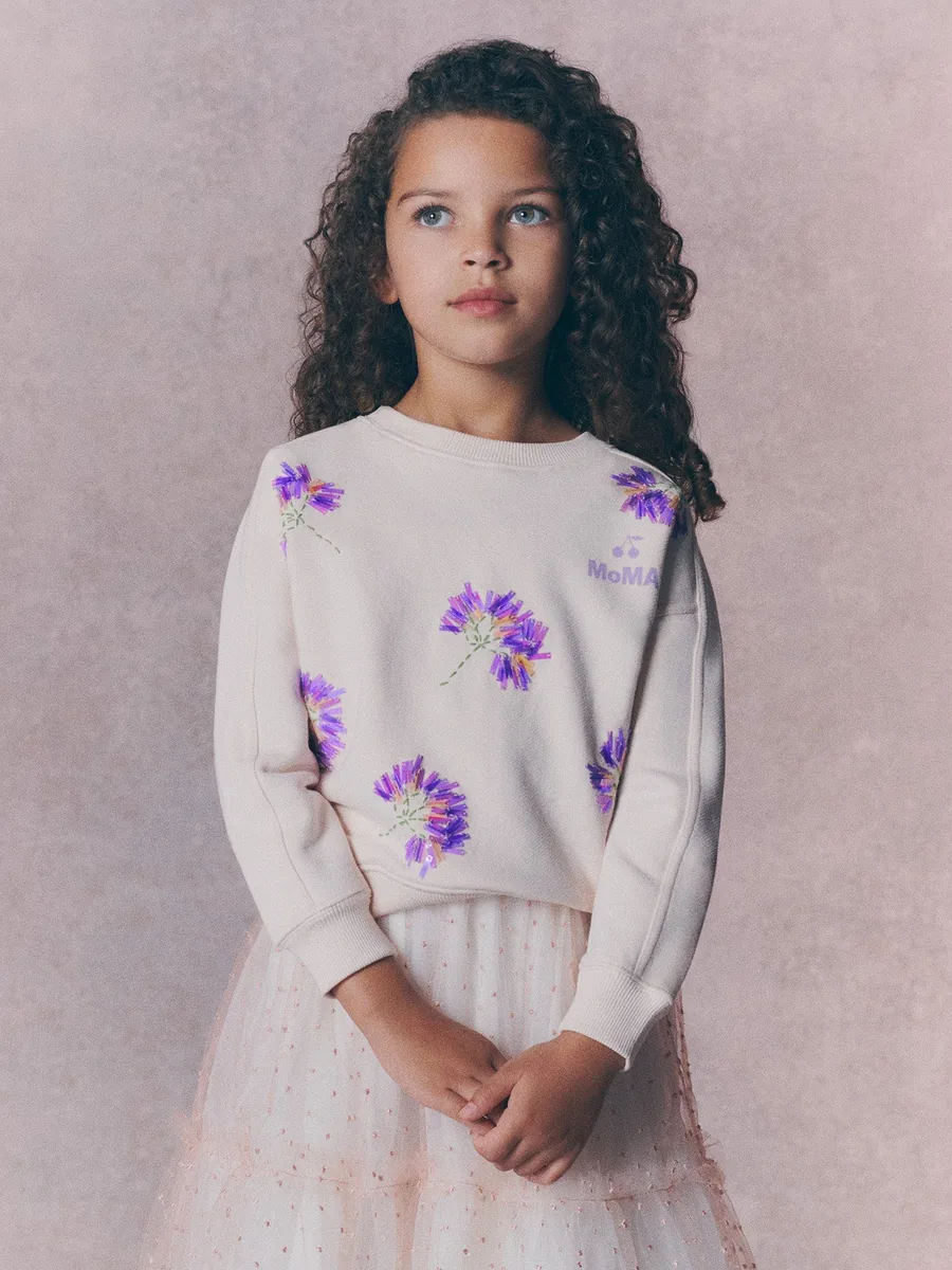 Niña con la sudadera de Bonpoint x MoMA con flores y perlas